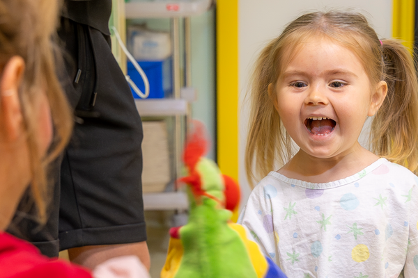 Ein kleines Mädchen, das lacht mit Clownin Lilo und ihrer Handpuppe.
