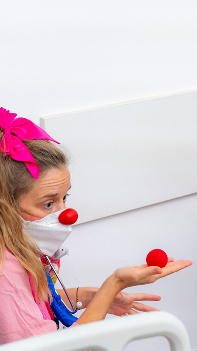 Clownin Paula hält eine rote Schaumstoffnase in ihrer rechten Hand.