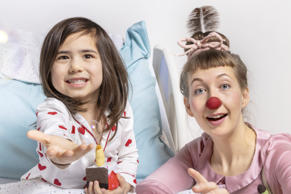 ROTE NASEN-Clownin Huberta und ein Kind, dass eine Spielzeugtorte in den Händen hält.