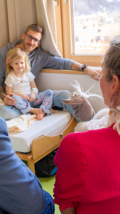 Laila und ihr Vater beobachten interessiert das Spiel mit der Handpuppe.