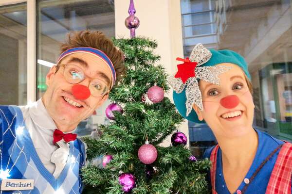 DIE ROTE NASEN-Clowns Bernhart und Betti vor einem geschmückten Weihnachtsbaum.