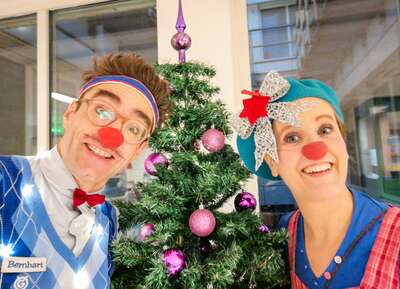 DIE ROTE NASEN-Clowns Bernhart und Betti vor einem geschmückten Weihnachtsbaum.