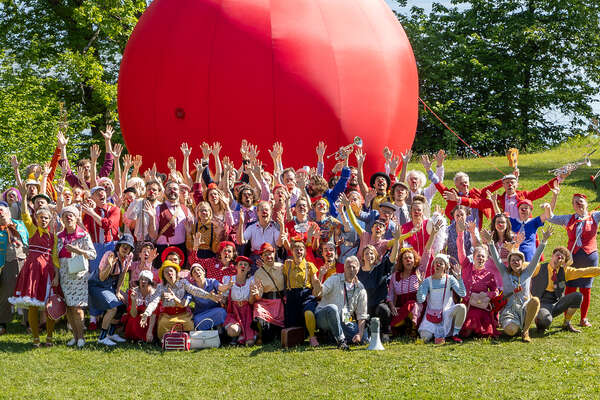 Gruppenfoto der ROTE NASEN-Clowns vor einer großen aufblasbaren roten Nase.