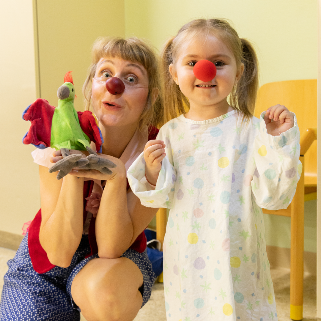 Ein kleines Mädchen mit einer roten Nase neben Clownin Lilo und ihrer Handpuppe.