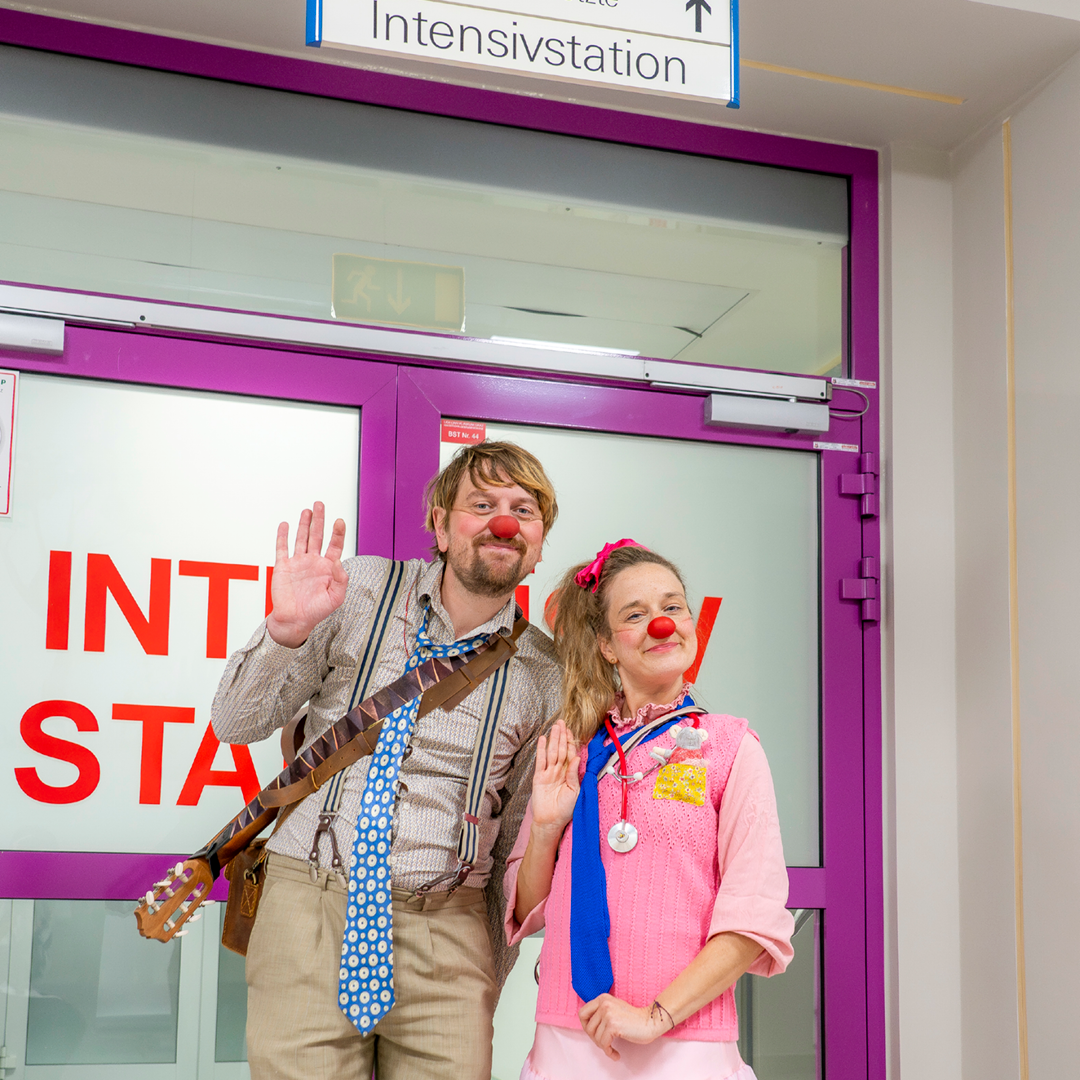Die ROTE NASEN-Clowns Lasse und Paula winken in die Kamera.