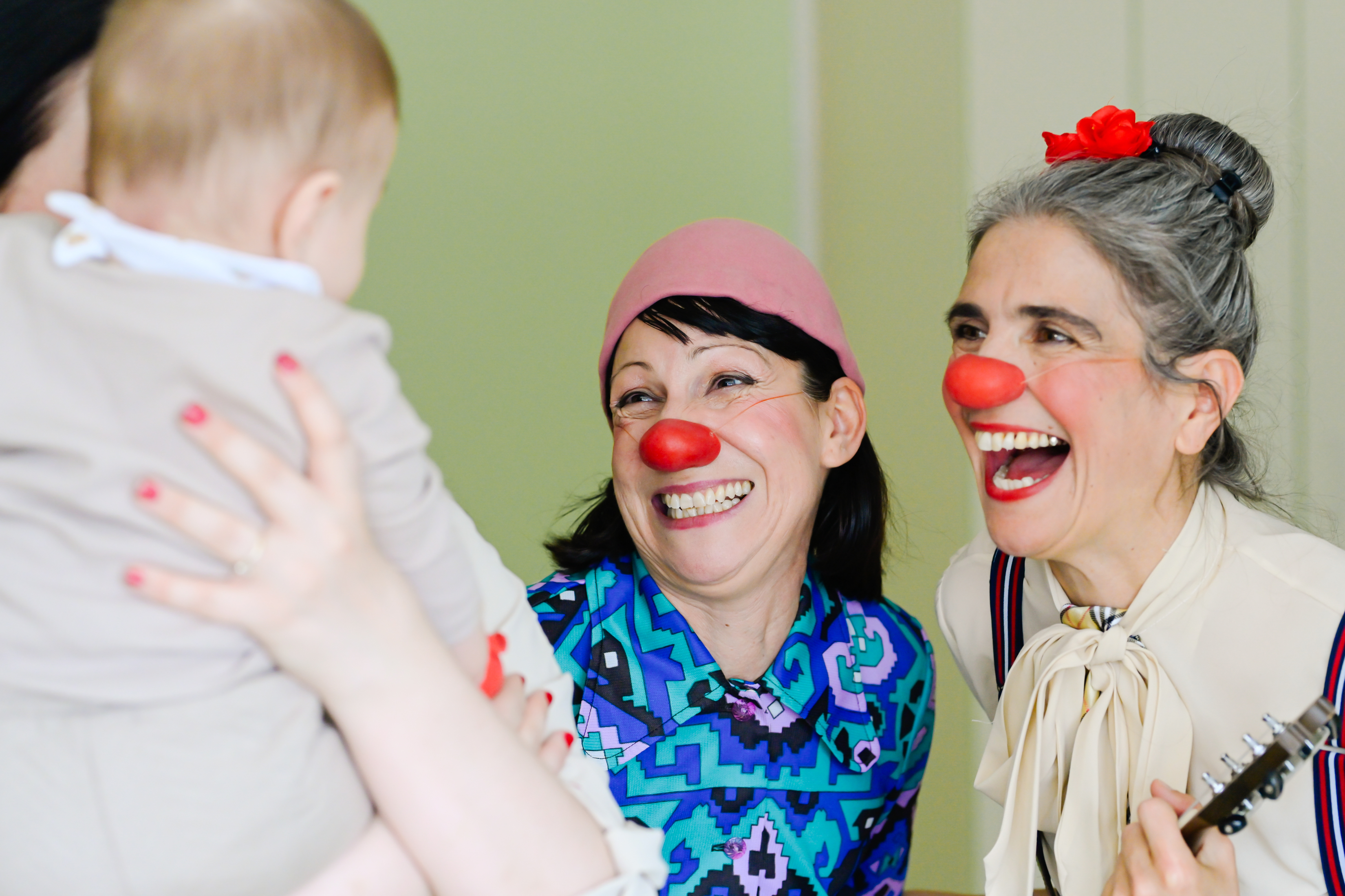 Die Clowninnen Mariangela und Rita, sowie eine Mutter, die ihr Baby am Arm hält.